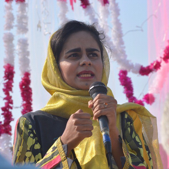 Wardah Noor speaking into a microphone at an outdoor event in Layyah